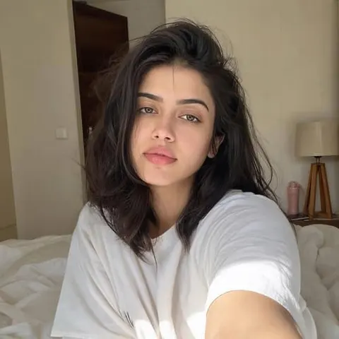 AI-generated influencer taking a relaxed bedroom selfie in a loose white T-shirt, with natural makeup and a soft indoor lifestyle aesthetic