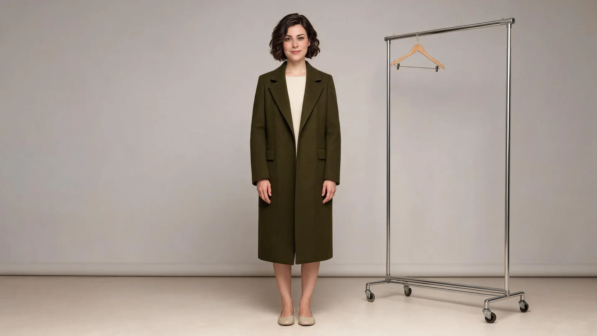 APOB-generated fictional fashion model wearing a dark olive coat in a studio beside a garment rack
