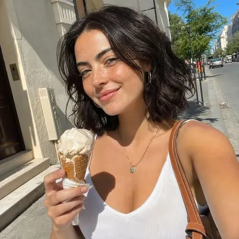 Virtual influencer holding an ice cream cone outdoors, wearing a white tank top and gold necklace on a sunny city street